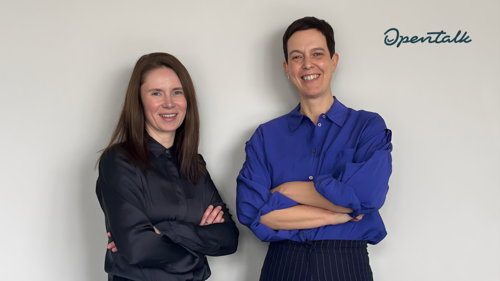 Agathe Hütter und Jutta Horstmann stehen lächelnd mit verschränkten Armen vor einer hellen Wand. Rechts oben ist das OpenTalk-Logo zu sehen.